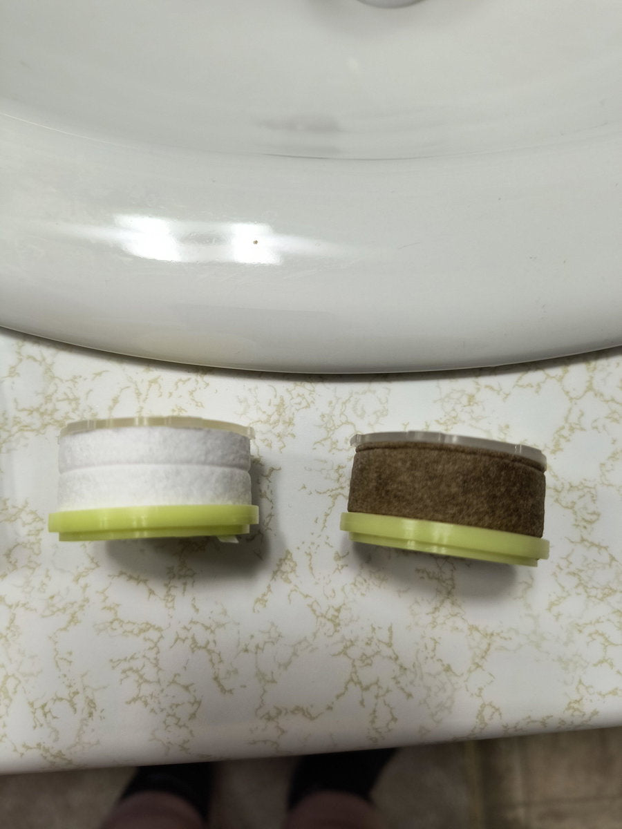 Customer photo: a new white cartridge next to a dark used cartridge on a bathroom counter